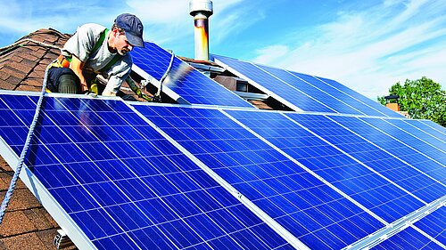 A man putting solar panels on a roof.