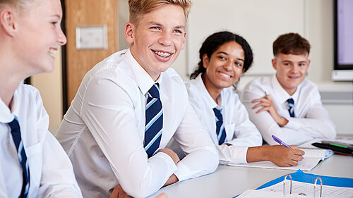 Four secondary school children sitting at a desk.