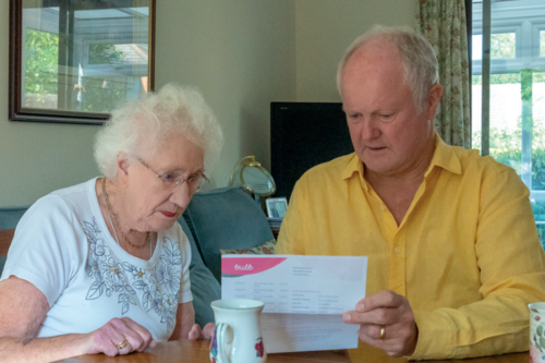Clive and an elderly lady looking at a bill
