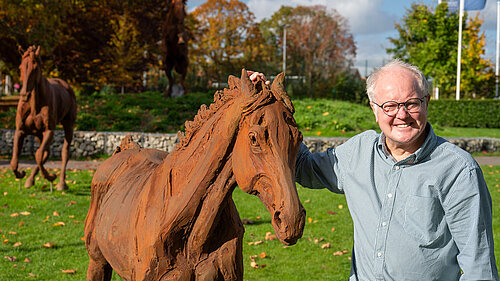 Clive Jones MP smiling with a sculpture of a horse at Arborfield Green