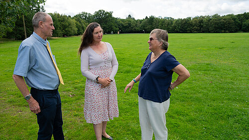 Prue and Paul talking to a resident in a green field