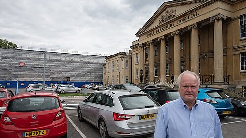 Clive Jones stood in the Royal Berkshire Hospital car park, frowning. In the background, scaffolding on part of the hospital building is visible.