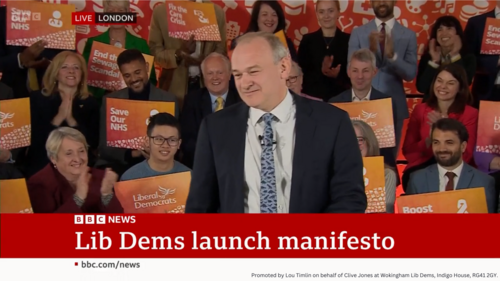Ed Davey launching manifesto on BBC with Clive in background